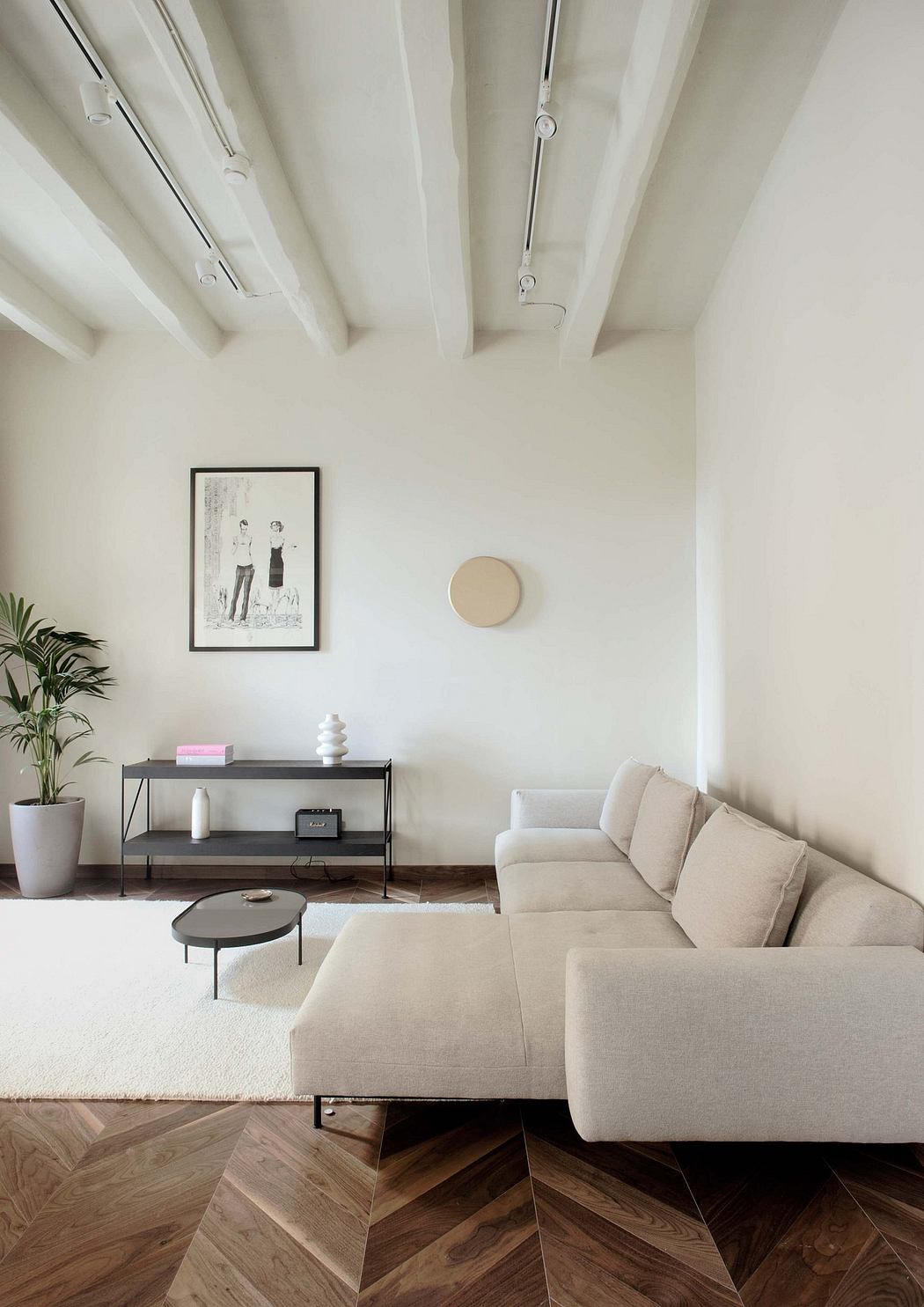 Minimalist living room with sleek shelving unit, plush sectional, and patterned wood flooring.