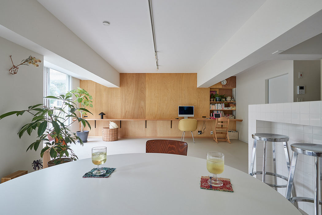 Minimalist open-concept living space with wooden wall panels, integrated desk, and natural lighting.