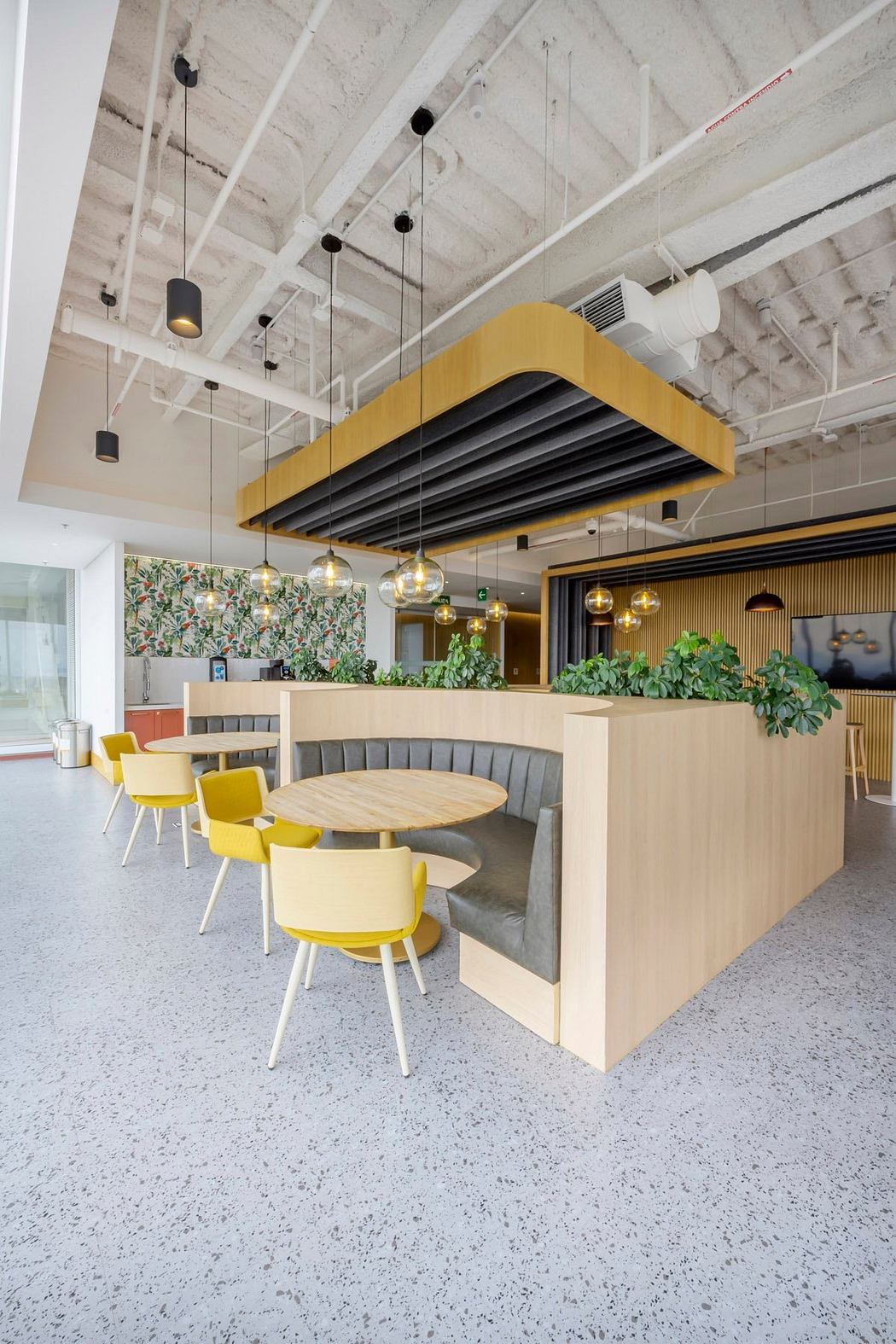 A modern, vibrant cafe with chic yellow chairs, lush greenery, and an industrial-style ceiling.