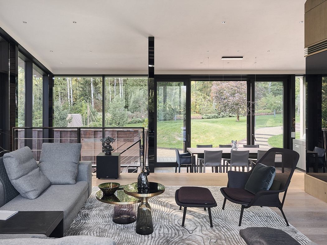 Sleek modern living room with full-length windows, minimalist furniture, and lush outdoor view.