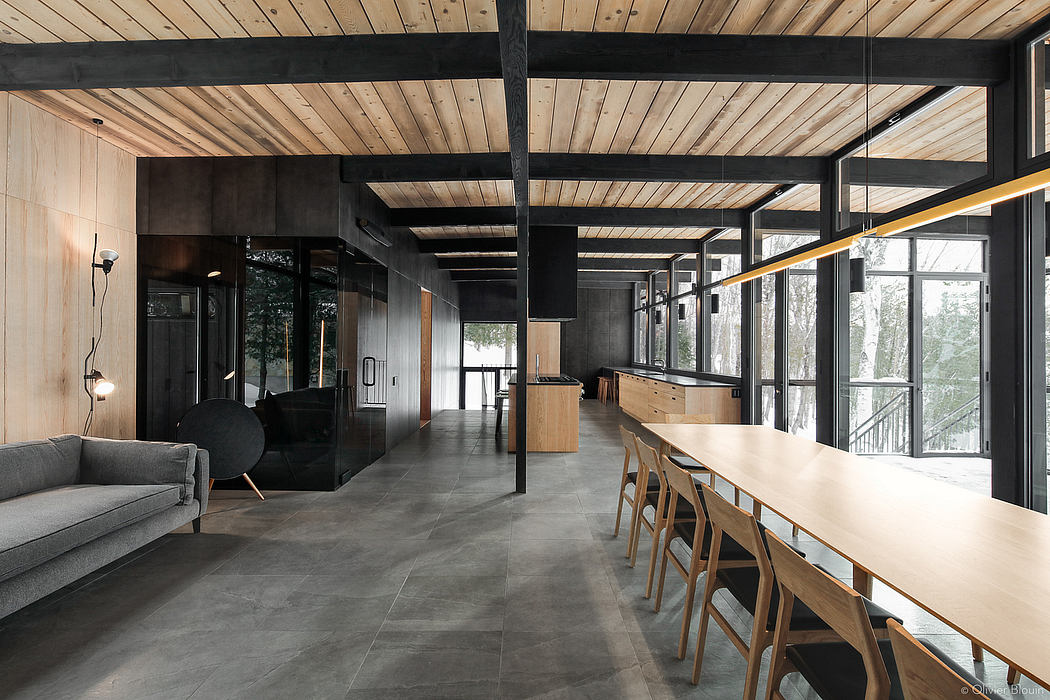 Spacious modern interior with wood-paneled ceilings, black beams, and large windows.