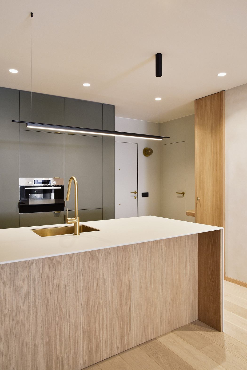 Contemporary kitchen with sleek gray cabinets, wood accents, and a gold faucet.