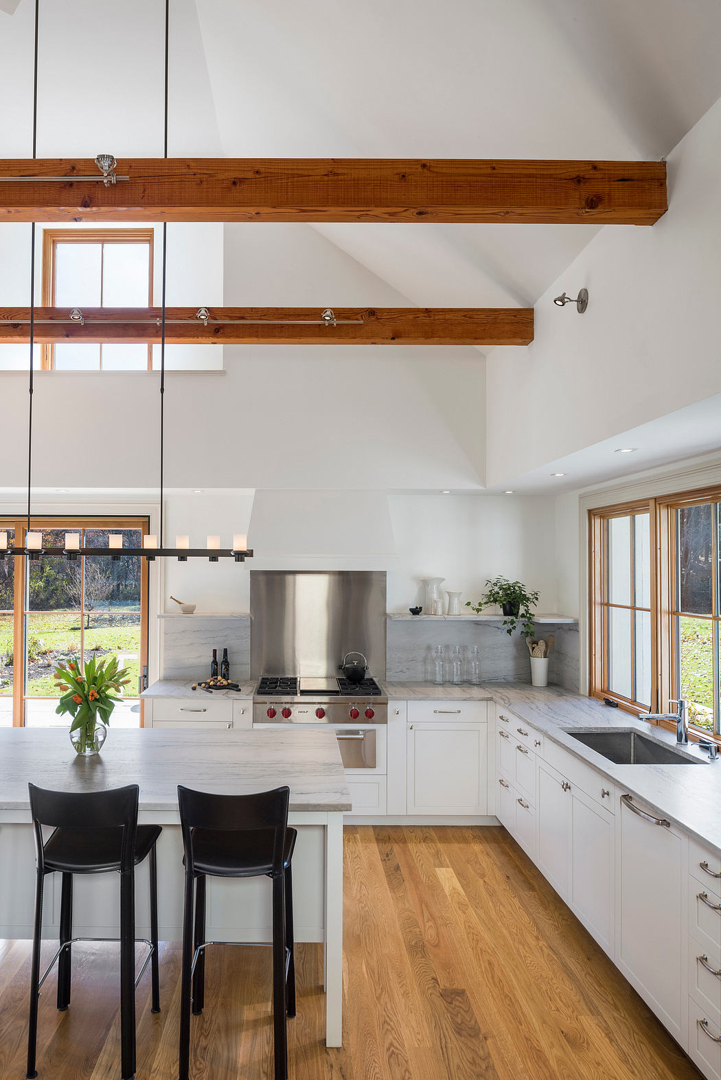 Bright and airy kitchen with exposed wood beams, modern appliances, and hardwood floors.