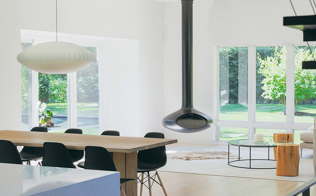 Airy, modern living space with large windows, minimalist furnishings, and suspended lighting.