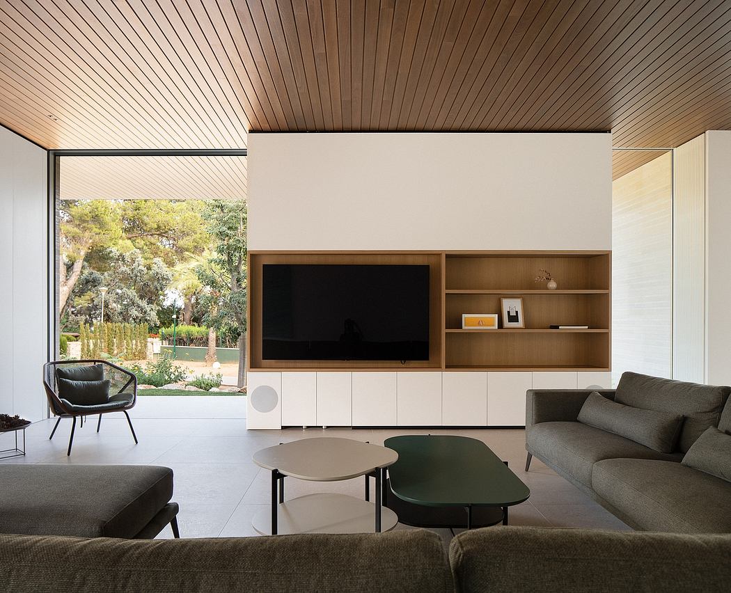 Modern living room with wood-paneled walls, built-in media unit, and large windows overlooking a garden.