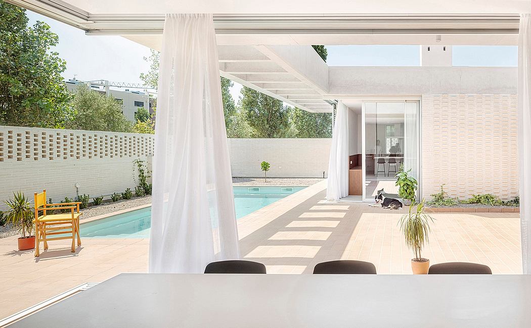 Minimalist architectural design with pool, patio, and lush greenery visible through the doors.