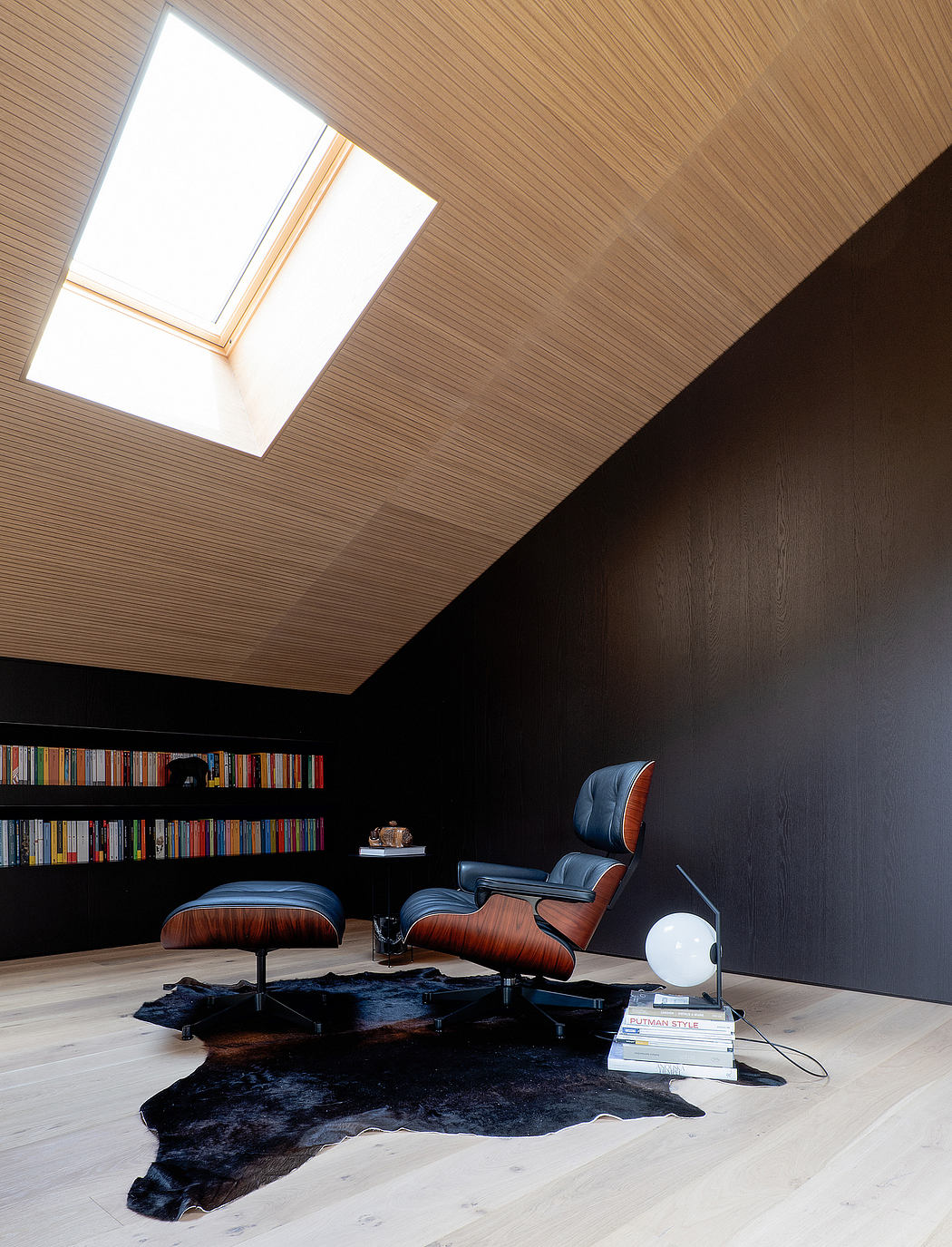 Modern loft-like space with skylights, built-in bookshelves, and a comfortable leather lounger.
