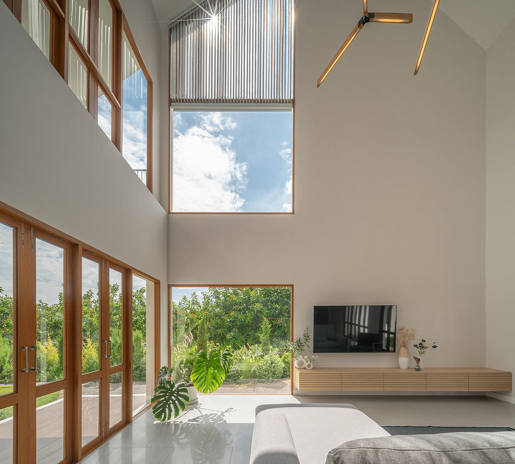 Spacious modern living room with lofty ceilings, large windows, and sleek wood furnishings.