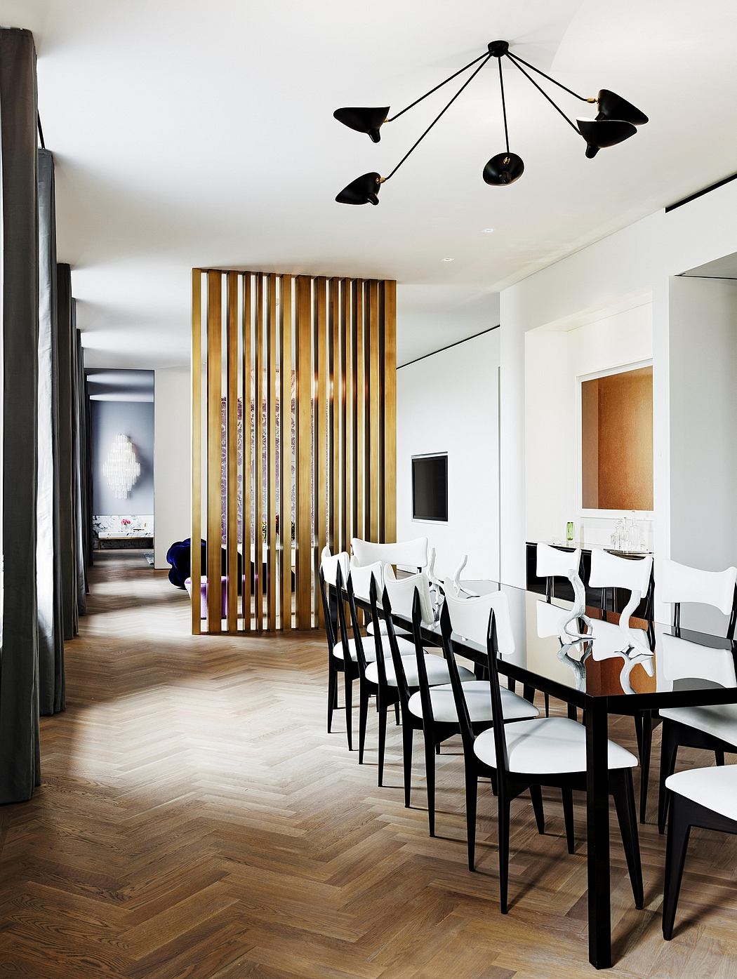 Contemporary dining room with modern lighting fixture, wood slats divider, and herringbone wood flooring.