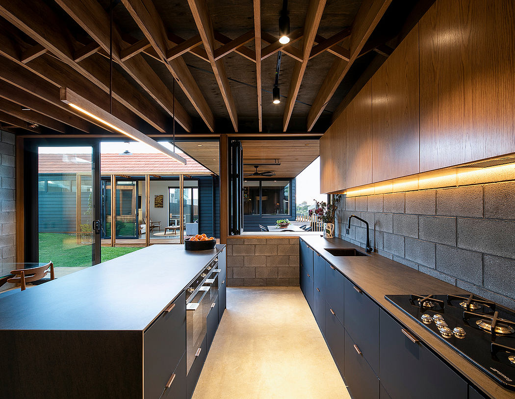 Spacious modern kitchen with wooden ceiling beams, dark cabinetry, and large windows overlooking the backyard.
