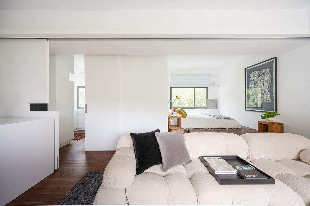 Spacious modern bedroom with minimalist furniture, large window, and artwork on wall.