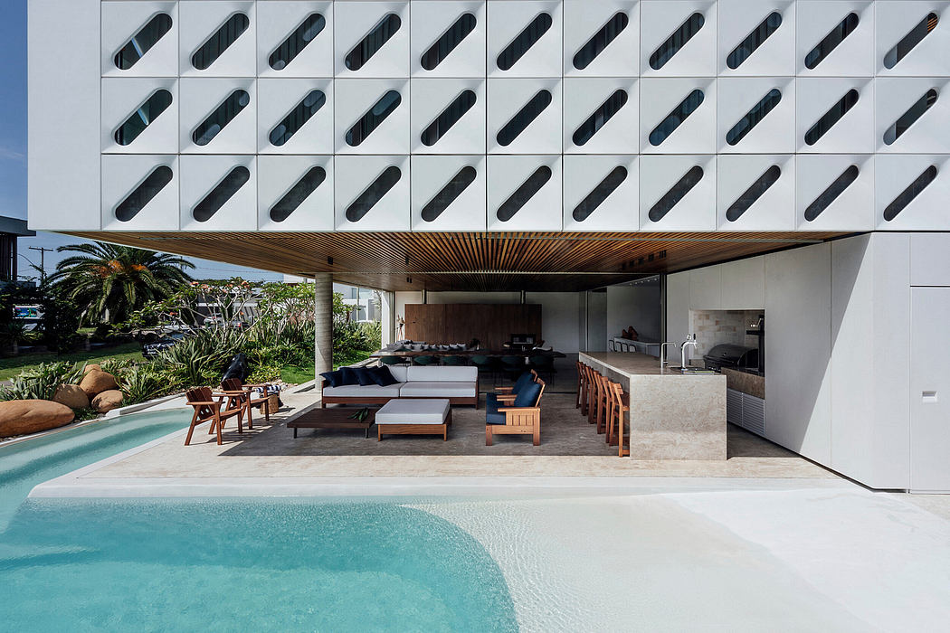 A modern outdoor living space with a wooden canopy, pool, and comfortable seating areas.