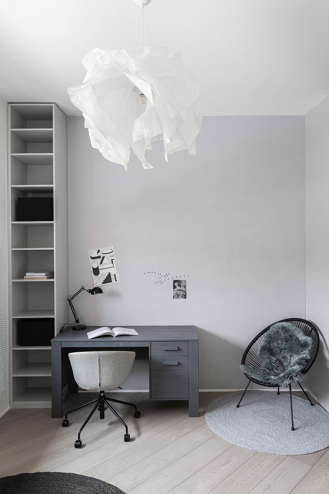 A minimalist home office with a gray desk, shelving, and a fur-covered chair.