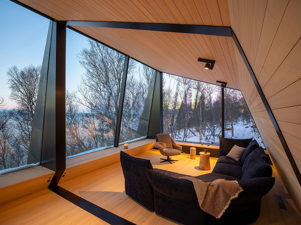 Panoramic glass walls frame a cozy winter scene, accented by a warm-toned wood interior.