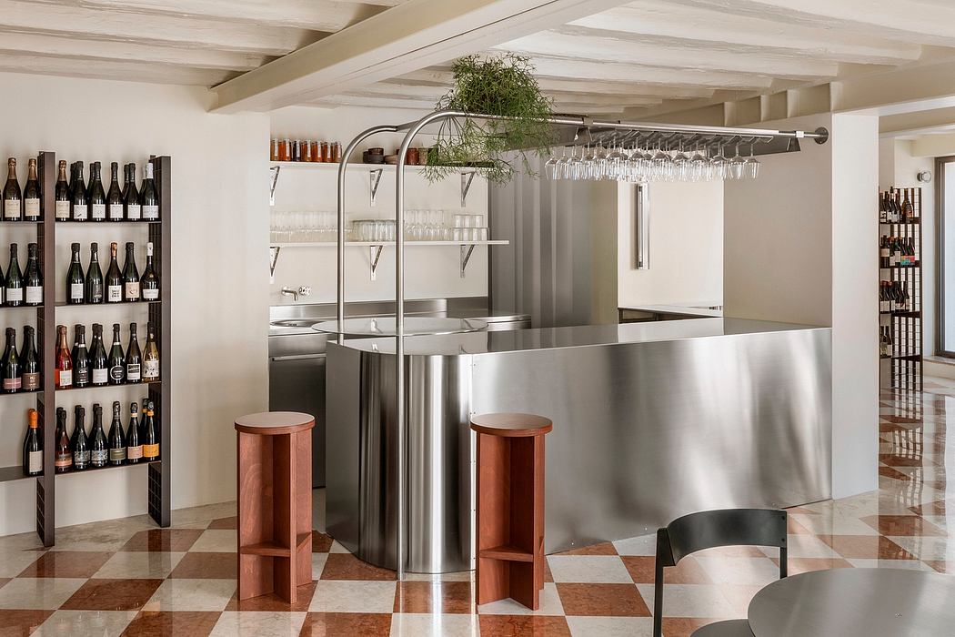 Minimalist bar setup with stainless steel counters, wooden stools, and shelves showcasing wine bottles.