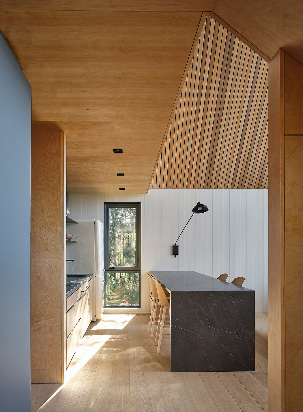 Wooden panels and minimalist kitchen island with large window frame natural setting.