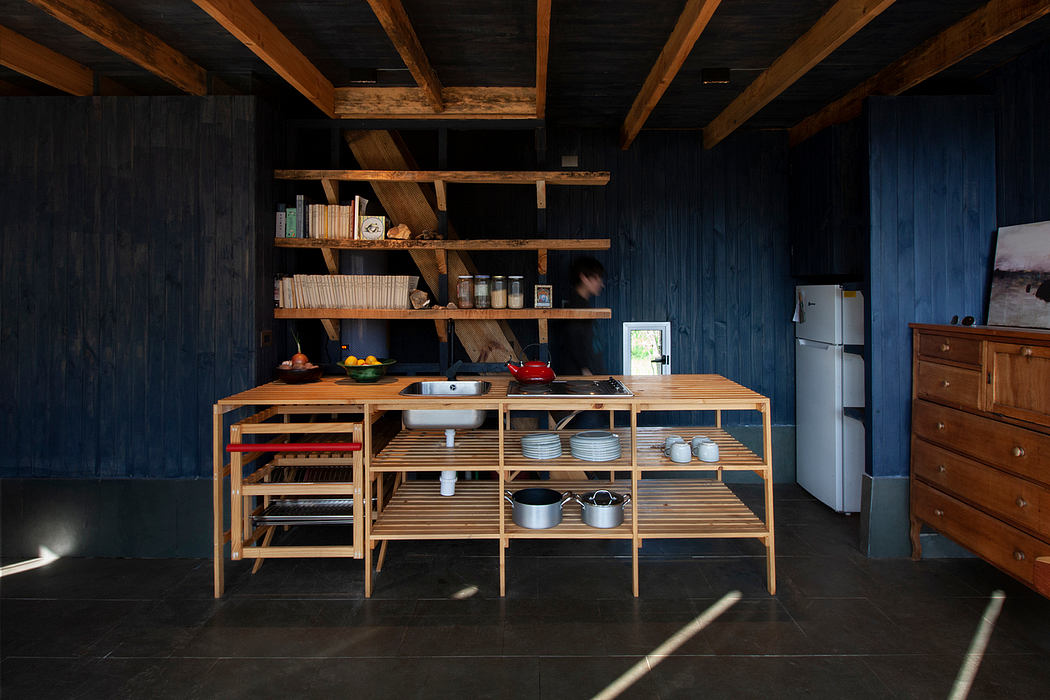 A rustic, timber-framed kitchen with open shelving and a wooden island, set against dark walls.
