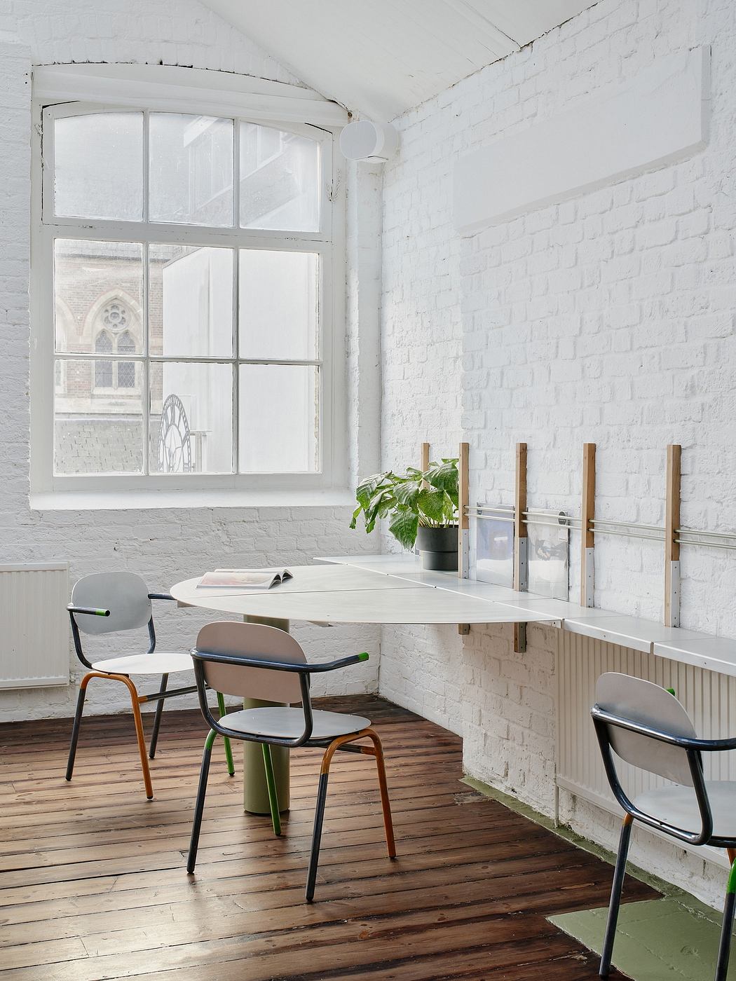 Bright, spacious room with large window, white brick walls, and eclectic furniture.
