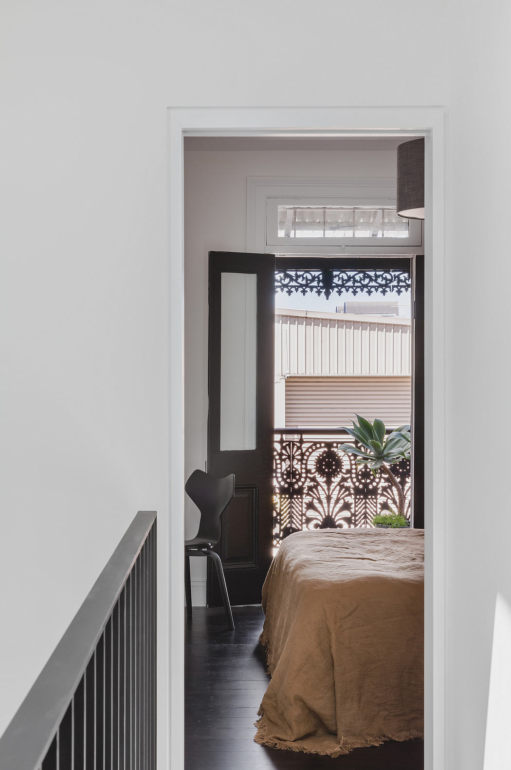 Cozy bedroom with ornate door frame, contrasting textures, and natural elements.