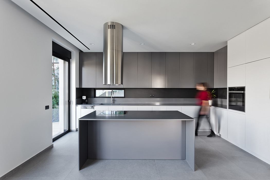 A sleek, modern kitchen with minimalist cabinets, a large central island, and stainless steel appliances.