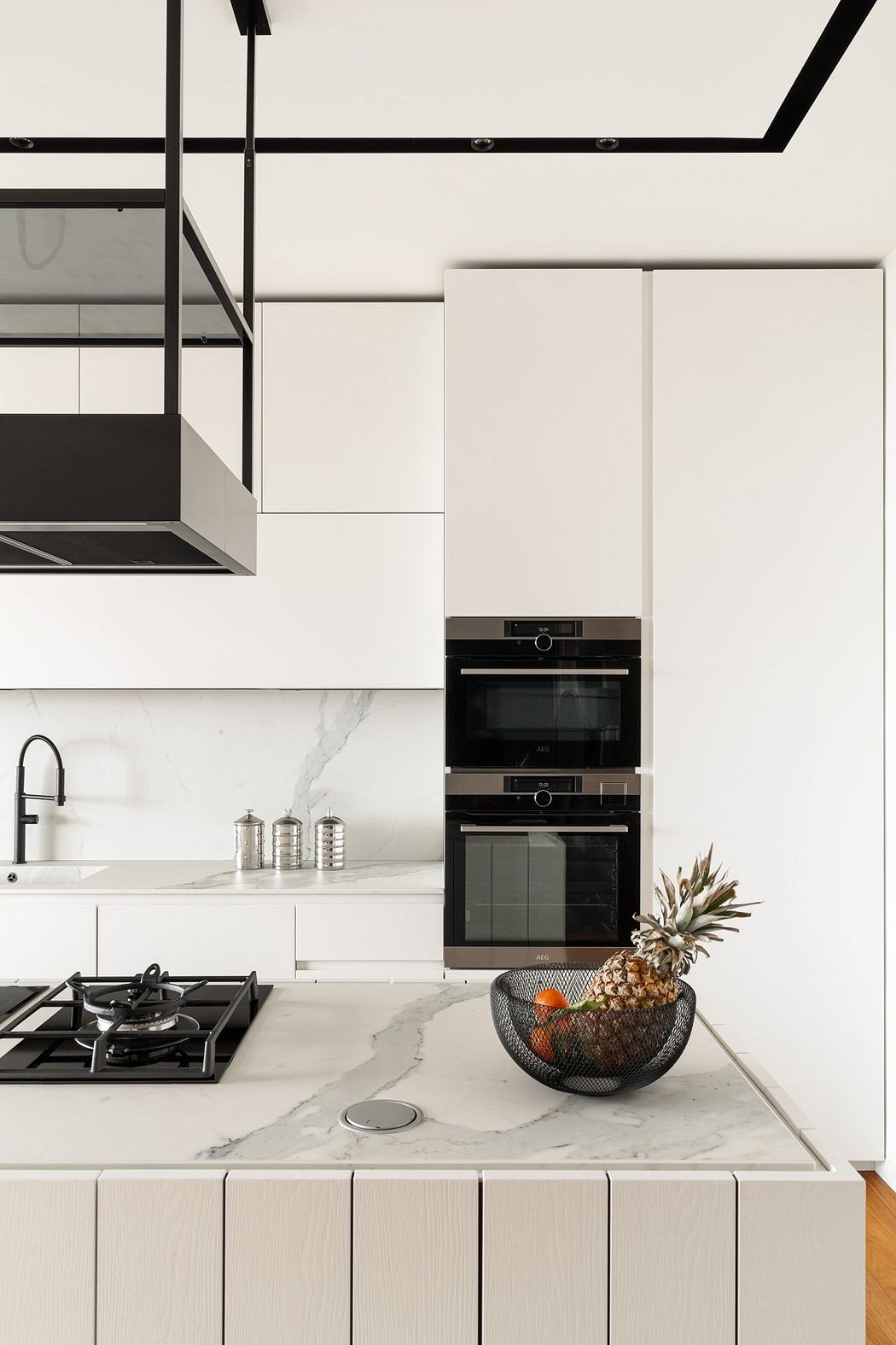 Modern kitchen with sleek white cabinets, black metal accents, and a marble countertop.