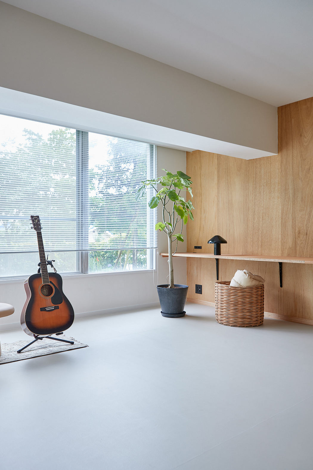 Modern, minimalist interior with natural textures, large windows, and a guitar.