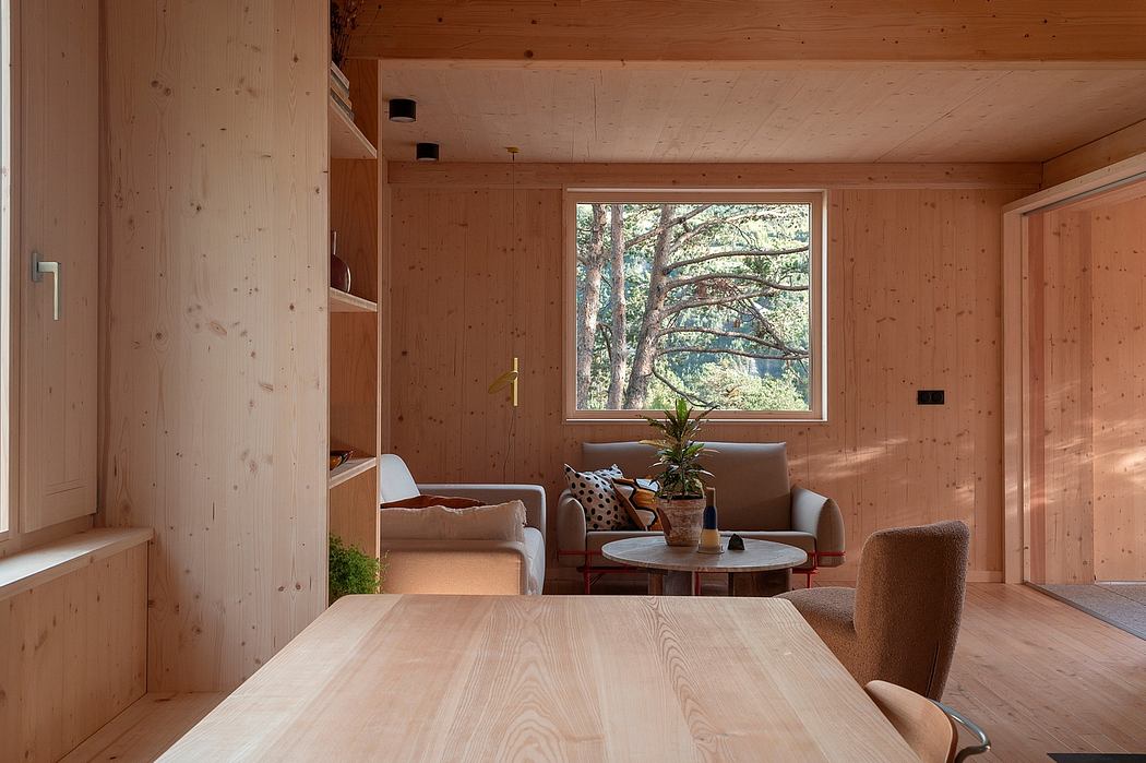 Cozy wooden cabin interior with a large window overlooking the forest.