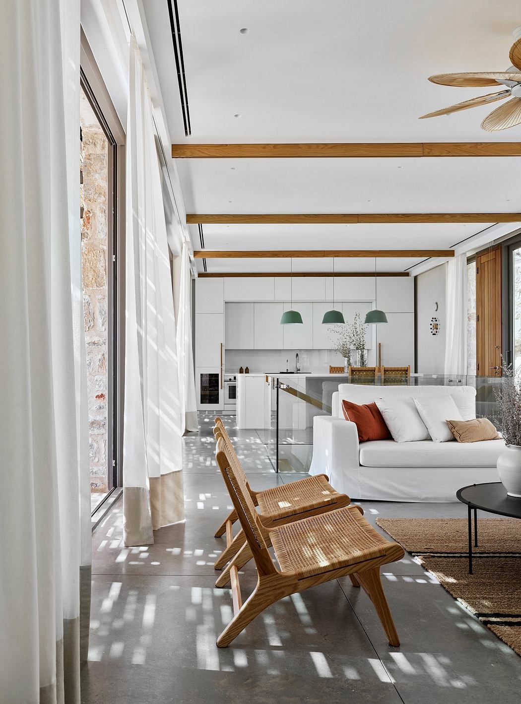 Airy open-concept space with exposed wooden beams, modern furniture, and stone accent wall.