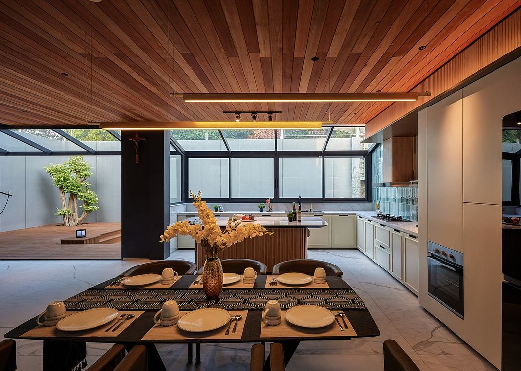 Modern, open-concept kitchen and dining area with wood paneled ceiling, glass walls, and sleek furnishings.