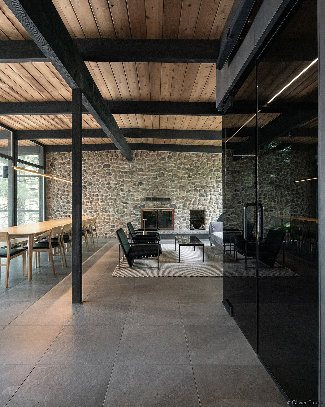 A cozy modern lodge interior with stone walls, wood beams, and sleek furnishings.