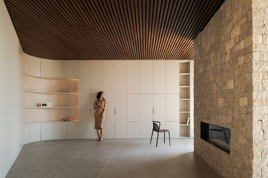 Minimalist living room with stone wall, wooden ceiling, and built-in shelving.