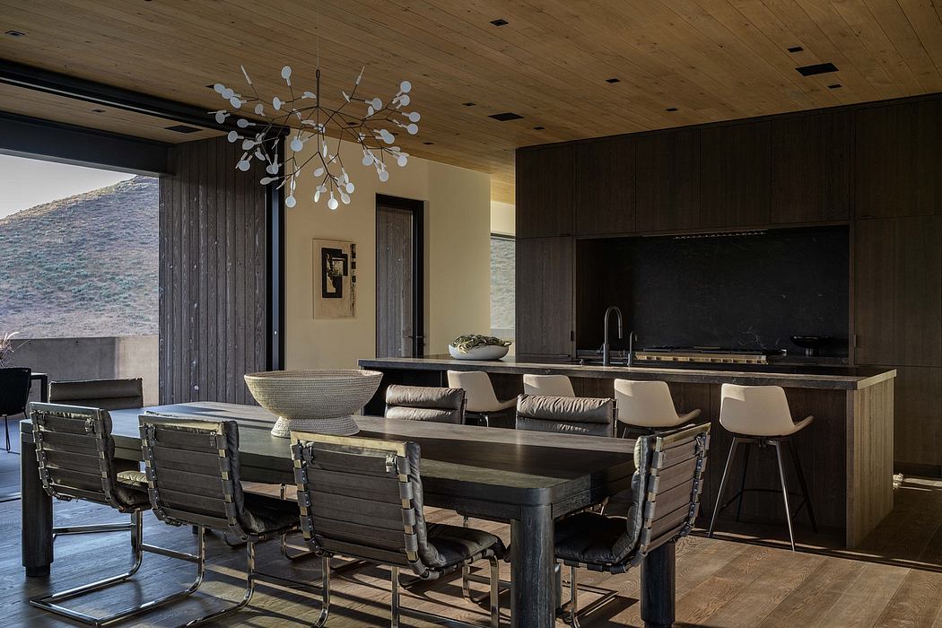 A modern, open-concept kitchen and dining area with a striking chandelierhttp:// and dark wood paneling.