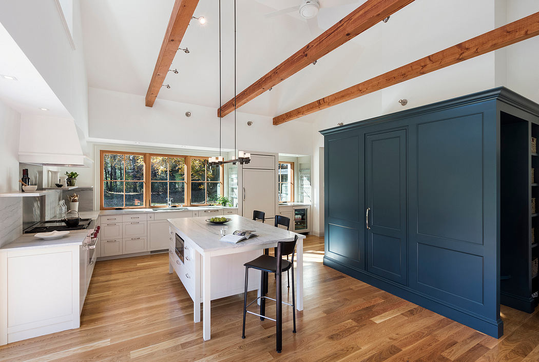 A spacious open-concept kitchen with wooden ceiling beams, a center island, and a large blue cabinet.