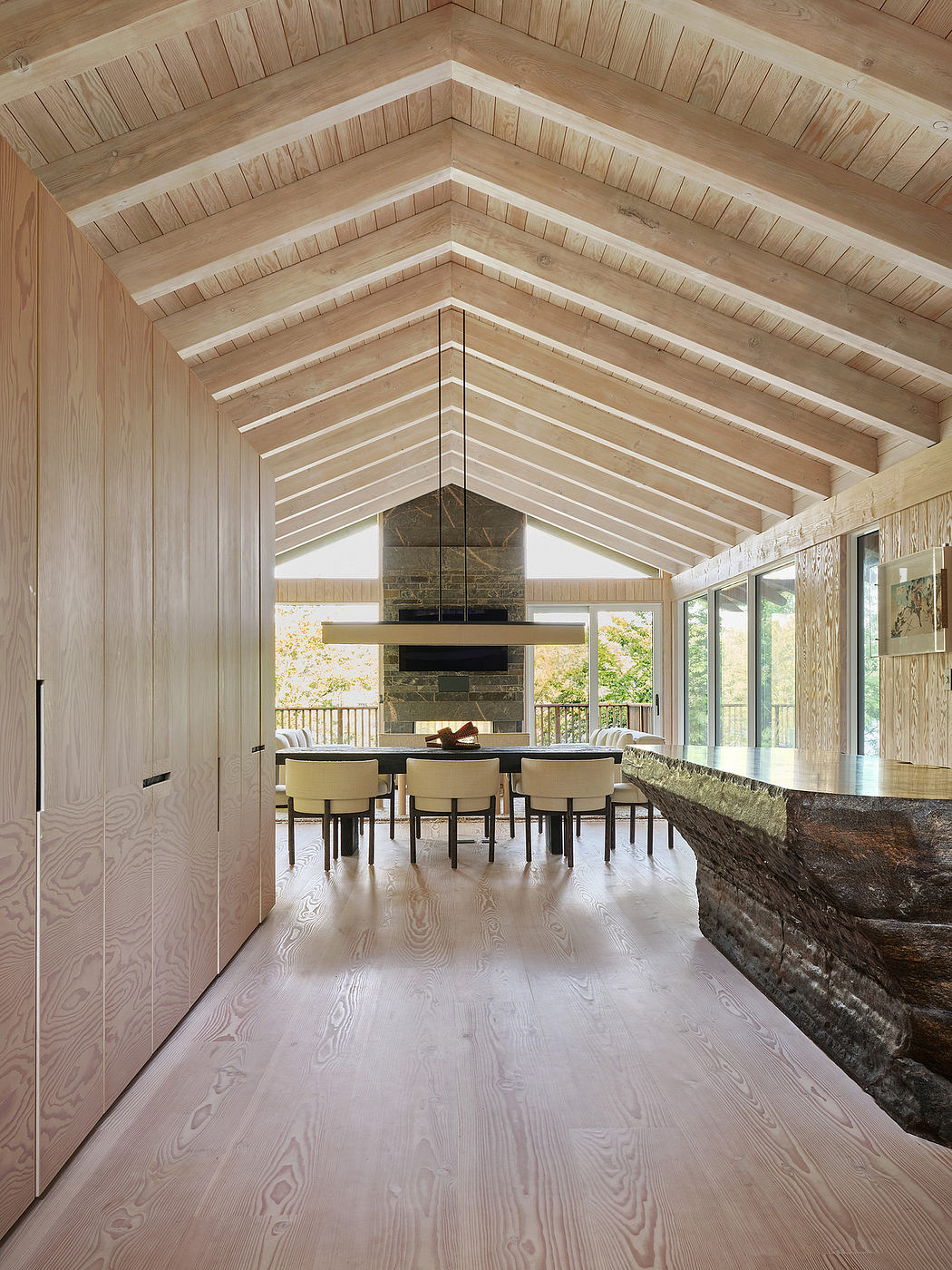 Spacious open-concept interior with vaulted wooden ceiling, stone fireplace, and wood floors.