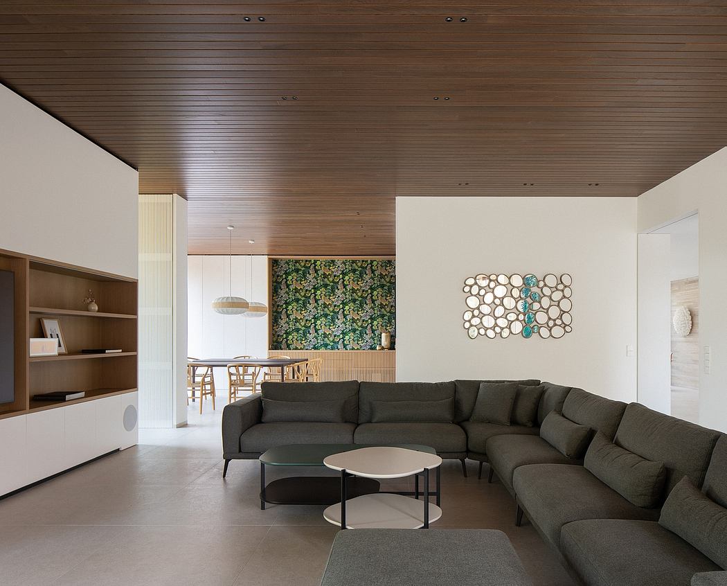 Modern living room with minimalist furniture, wood paneled ceiling, and green living wall.