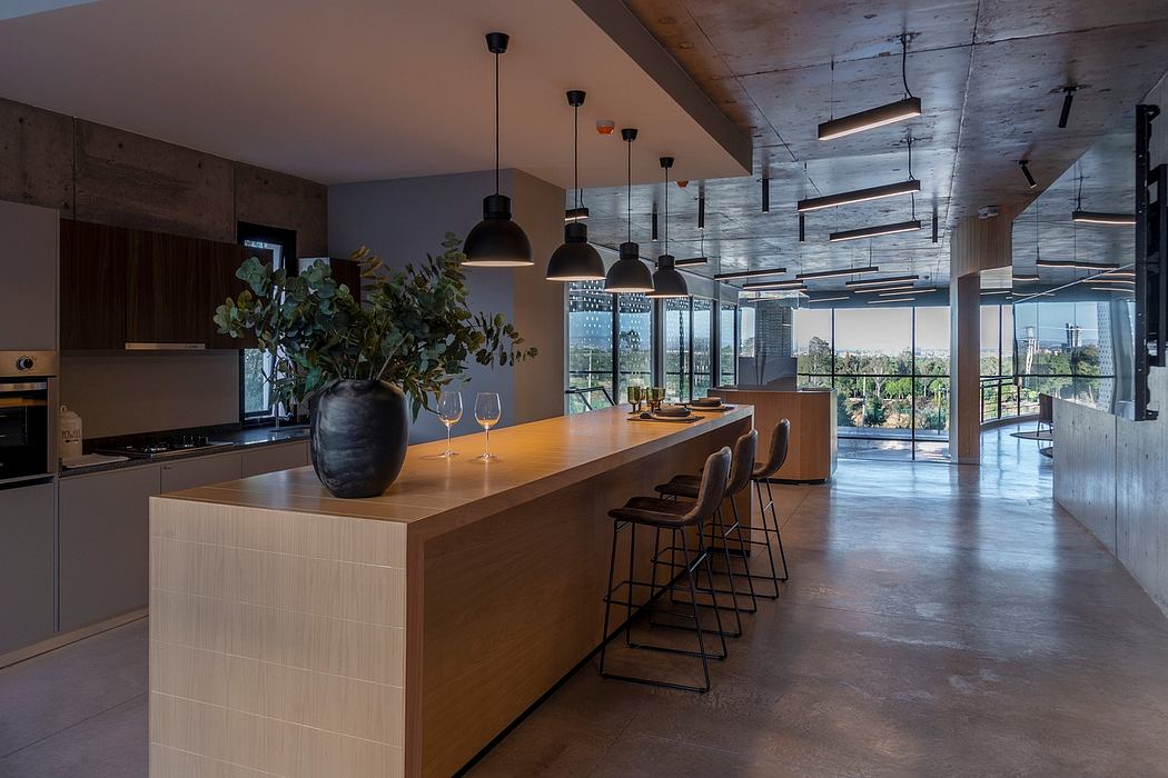 Sleek, modern kitchen with wooden bar, dangling lights, and large windows offering scenic view.