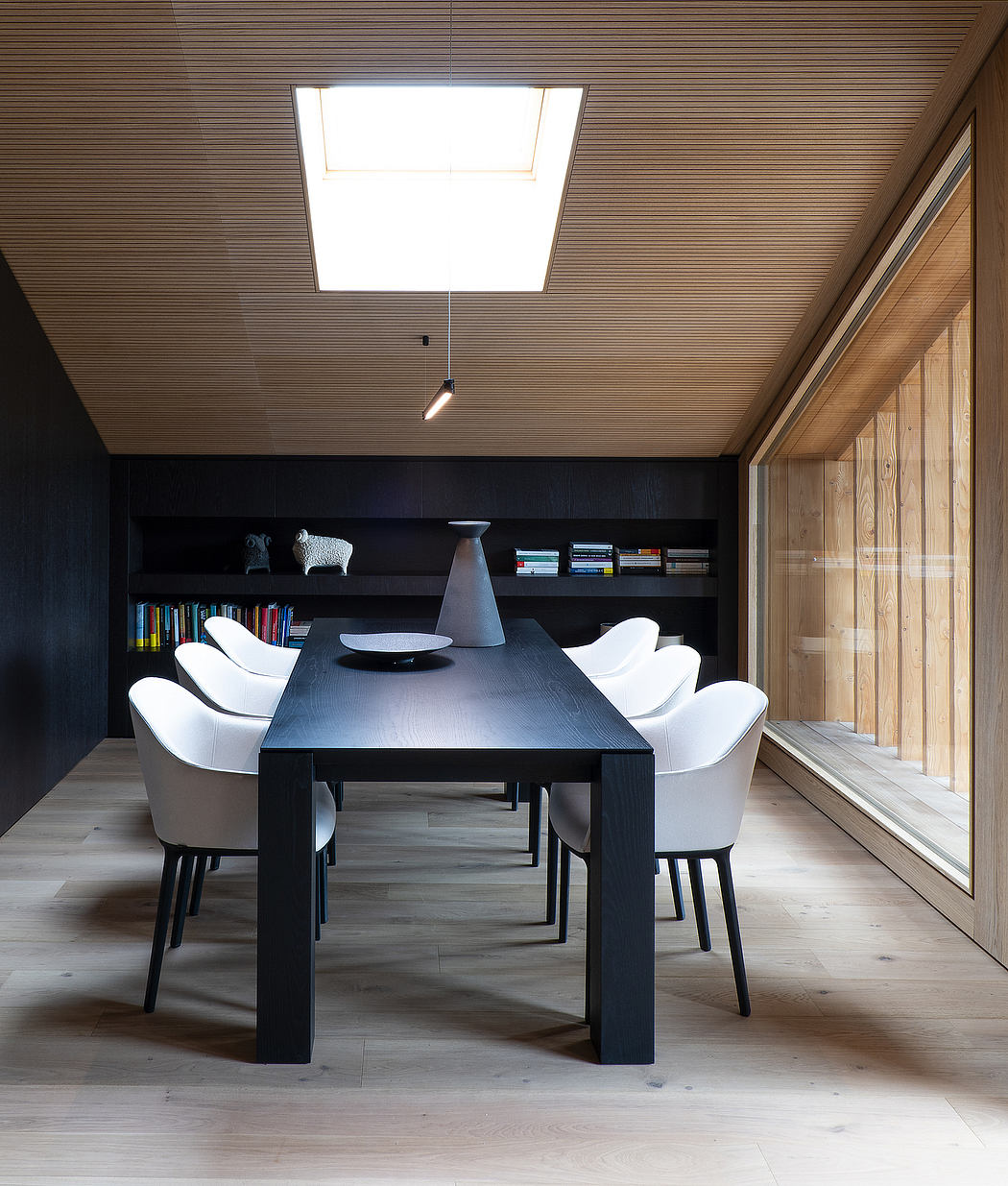 Sleek, modern dining area with a black table, white chairs, and built-in shelving.