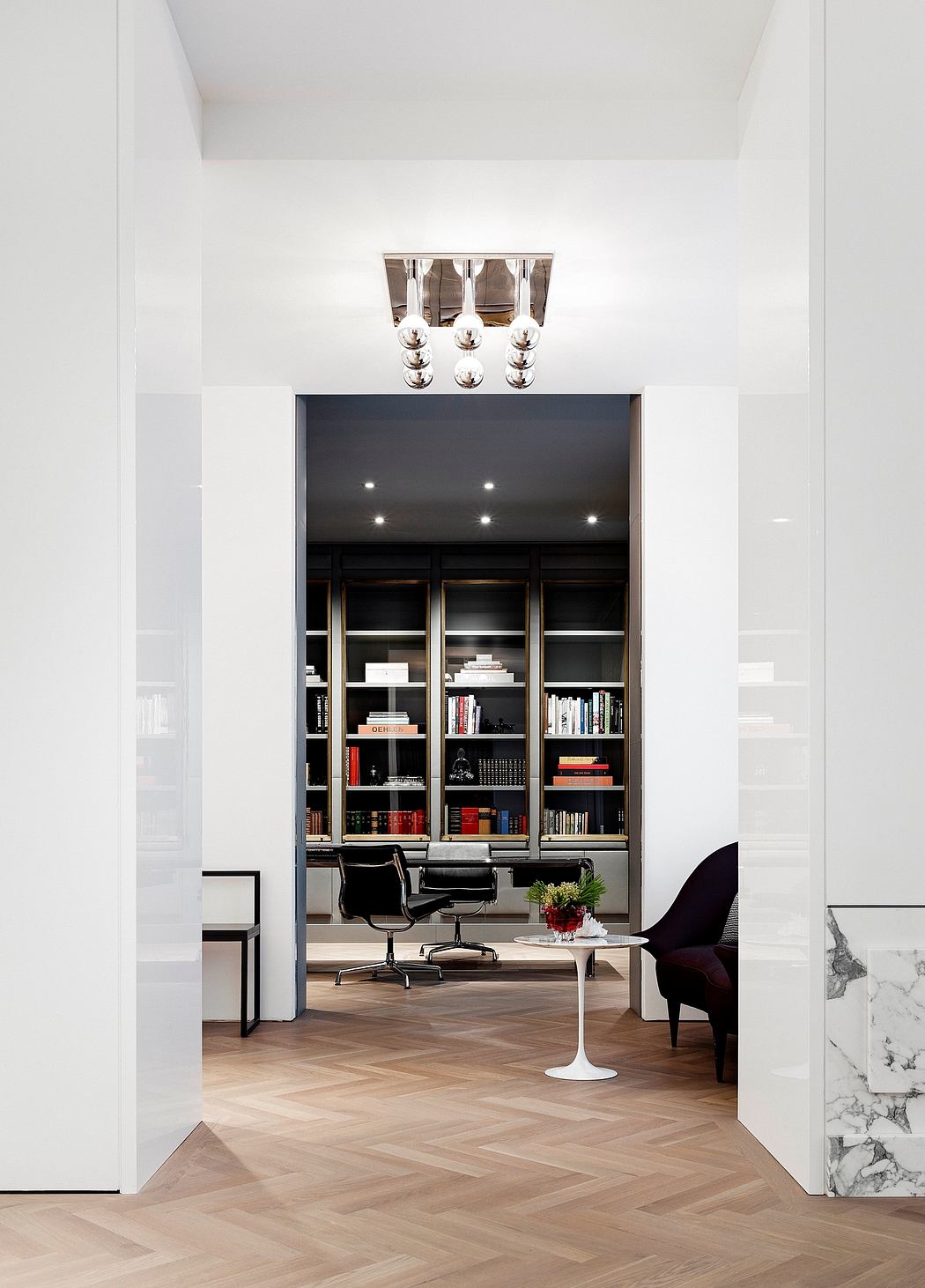Minimalist office space with dark built-in bookshelves, sleek lighting, and marble flooring.