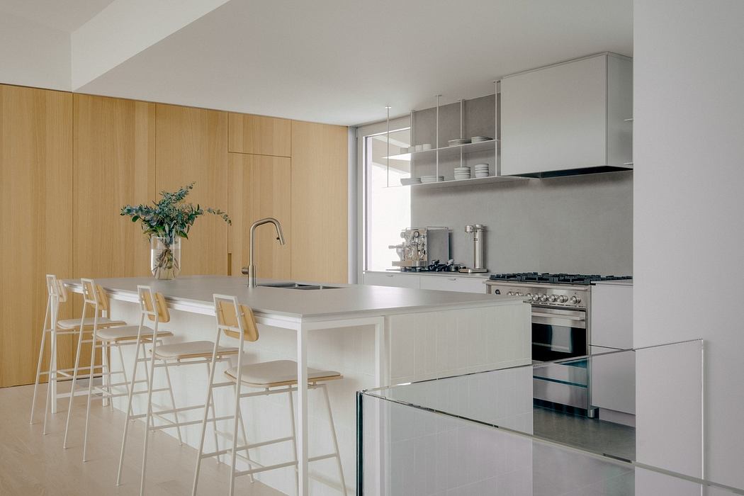 Modern, minimalist kitchen with clean, neutral tones, sleek cabinetry, and a central island.