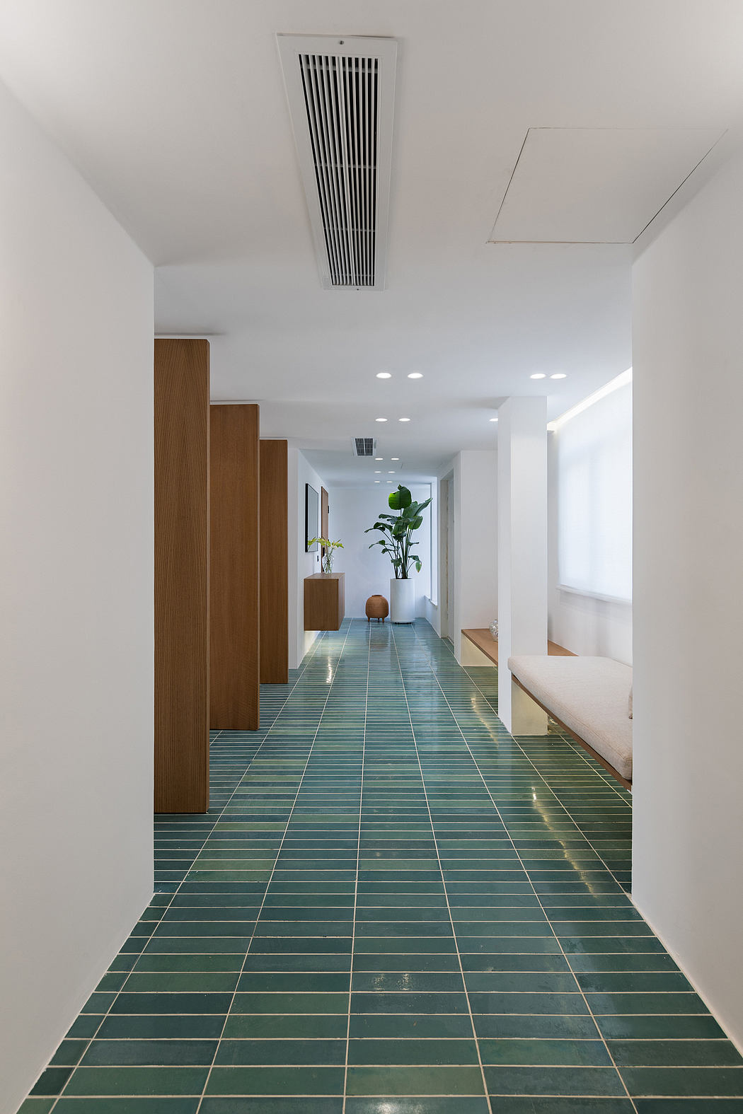 Sleek modern interior with wood accents, textured green tiles, and overhead ventilation.