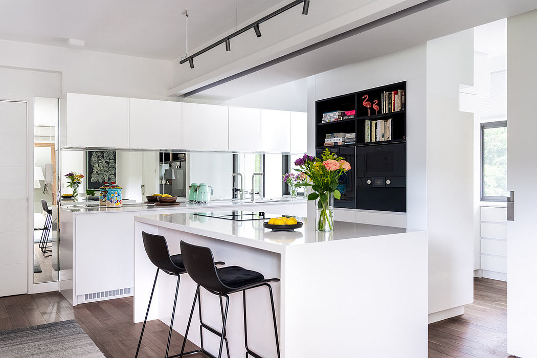 A modern, minimalist kitchen with sleek white cabinets, black accents, and a large central island.