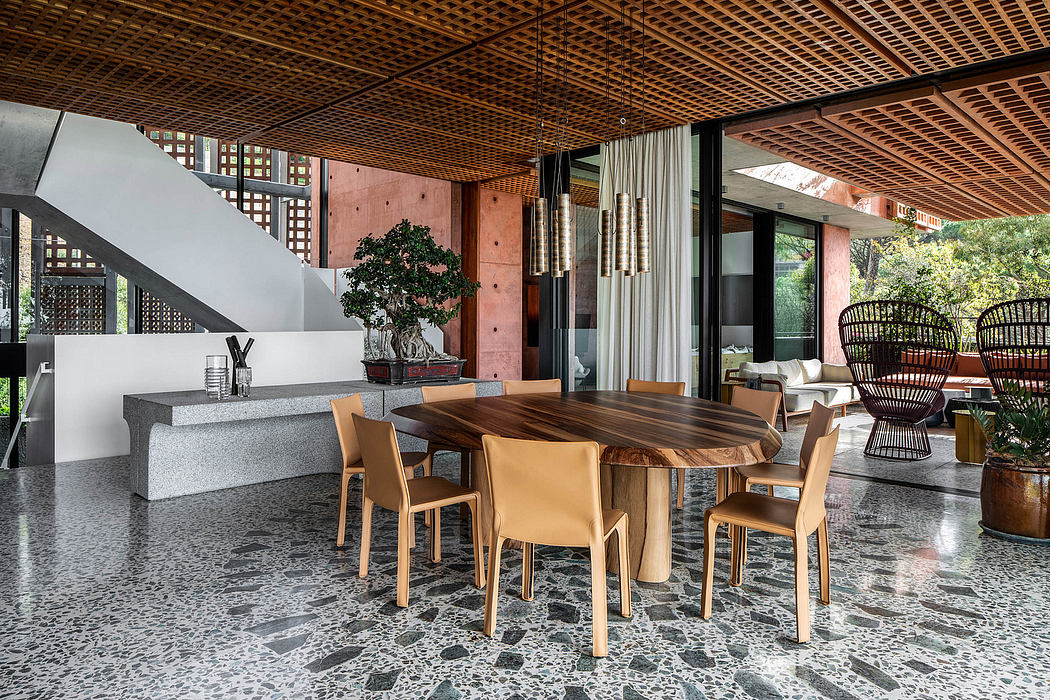 A modern, open-concept living space with a wooden dining table, rattan chairs, and a concrete accent wall.