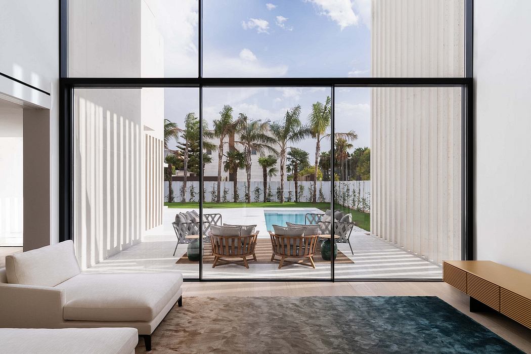 Modern interior with tall windows offering a view of a pool and palm trees outside.