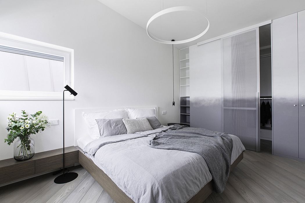 Spacious modern bedroom with circular lighting fixture, built-in closets, and wooden floors.