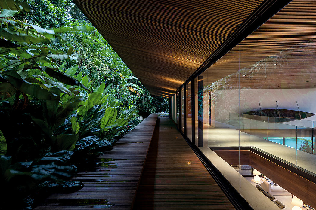 Lush, wooden walkway with modern glass-walled interior and pool overlooking greenery.