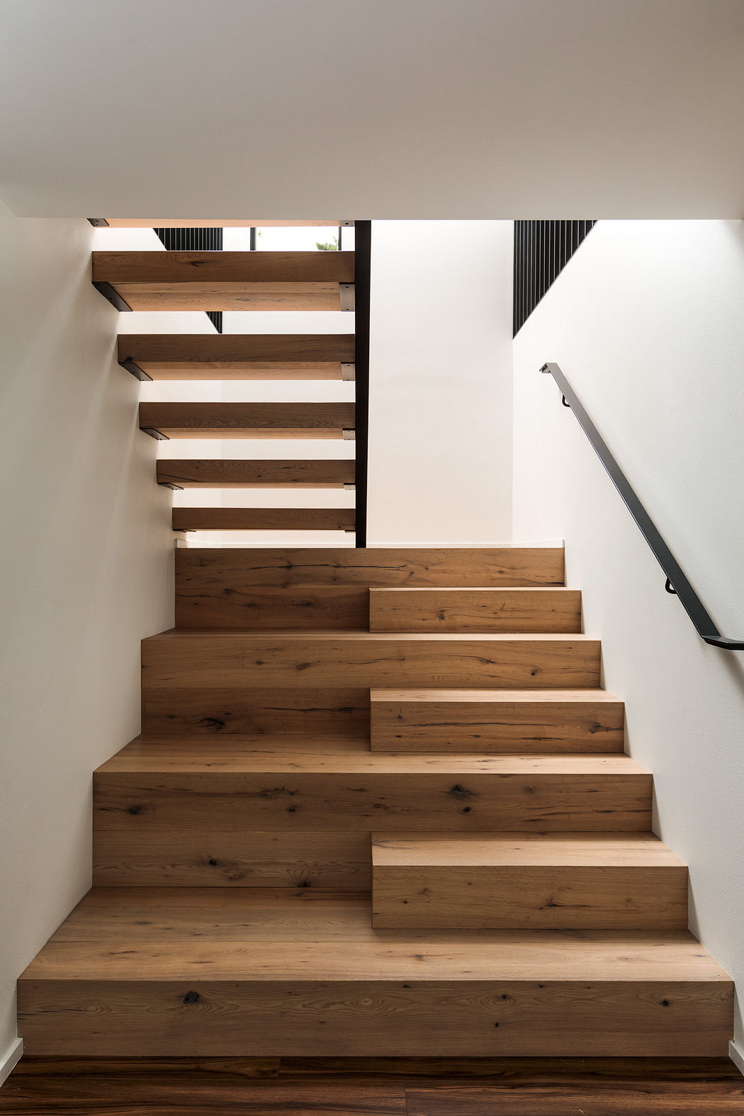 Wooden staircase with open riser design, creating a modern, minimalist aesthetic.