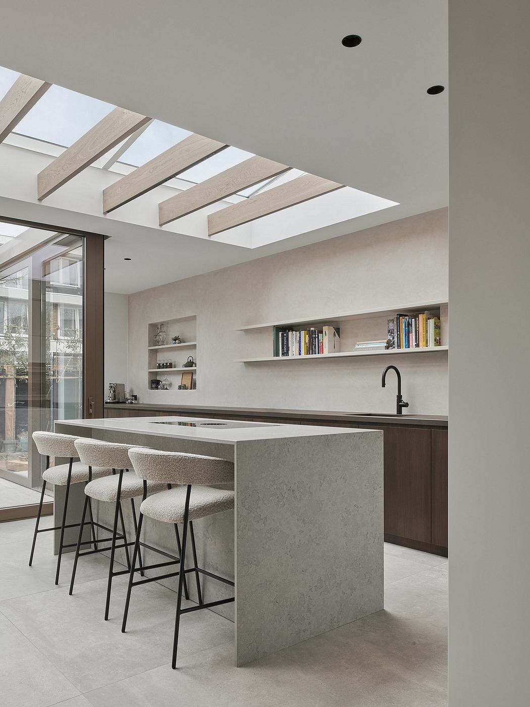 A modern kitchen with a sleek design, featuring a large skylight, shelves, and a minimalist island.