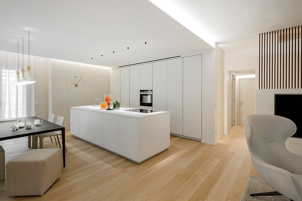 Sleek, modern kitchen with white cabinetry, wood floors, and minimalist decor.