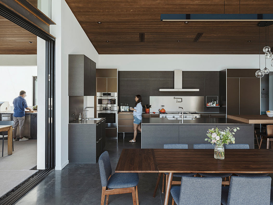 Sleek modern kitchen with dark cabinets, wood accents, and an open floor plan.