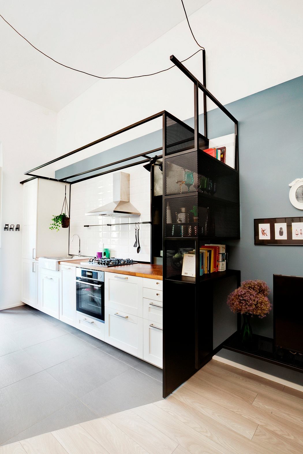 Modern open-plan kitchen with sleek black metal shelving, wood countertop, and appliances.